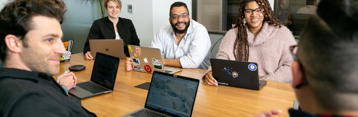 Entrevistadores sorrindo à volta de uma mesa com notebooks